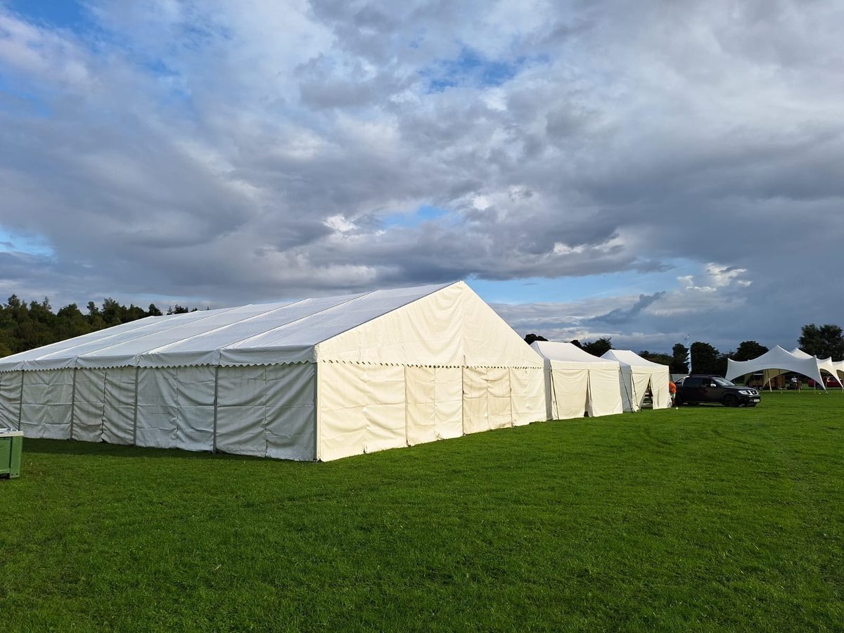 A run of white frame marquees on a field for a food festival