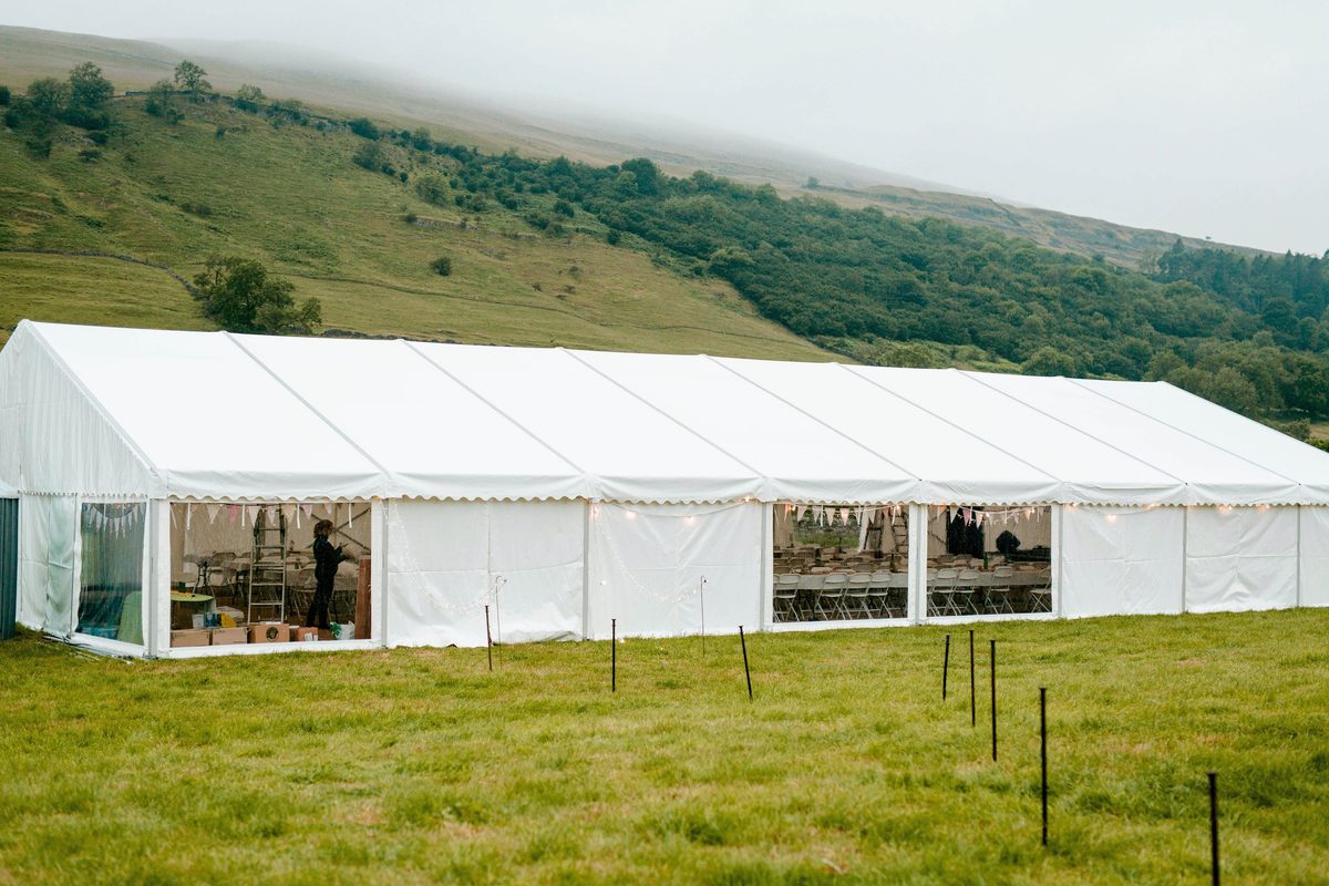 Long white clear span marquee set up for a wedding on a field in a Yorkshire valley