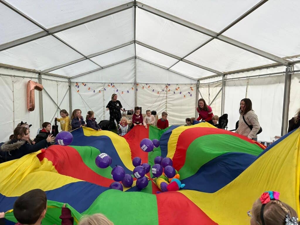 Clear span modular marquee in use for a childrens party, filled with balloons and enough room for a parachute party game.